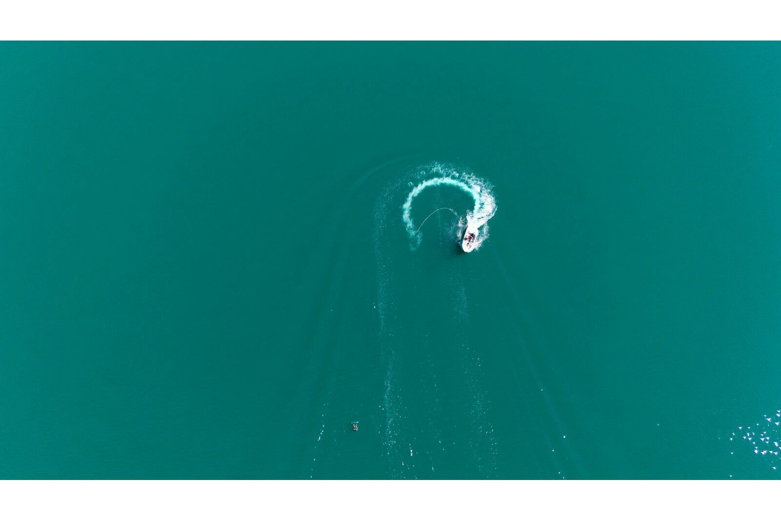 Luchtfoto van een boot die een strakke bocht maakt met circulaire wake op turquoise water