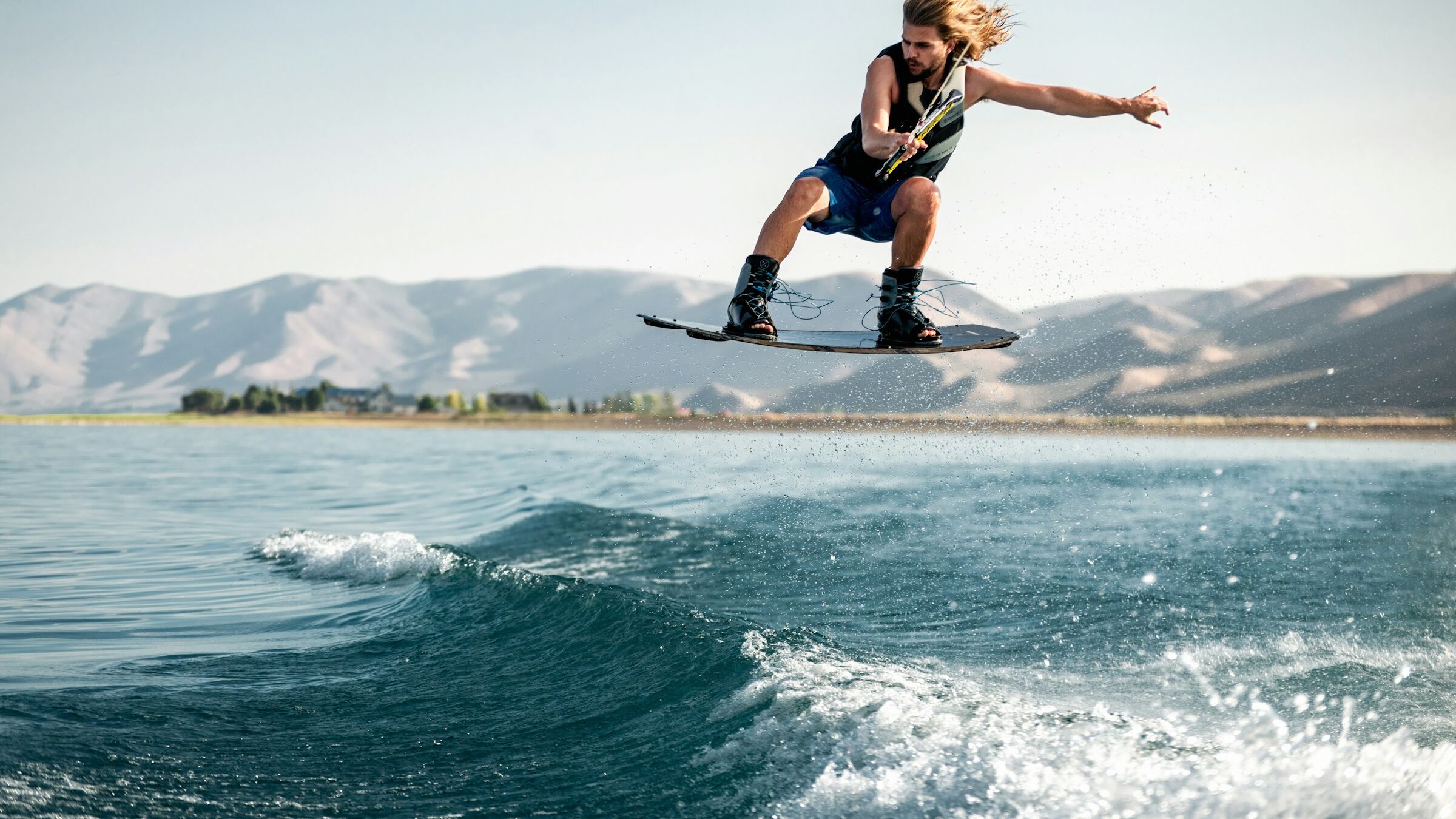 Wakeboarder op de Waal achter een motorboot met opspattende wake